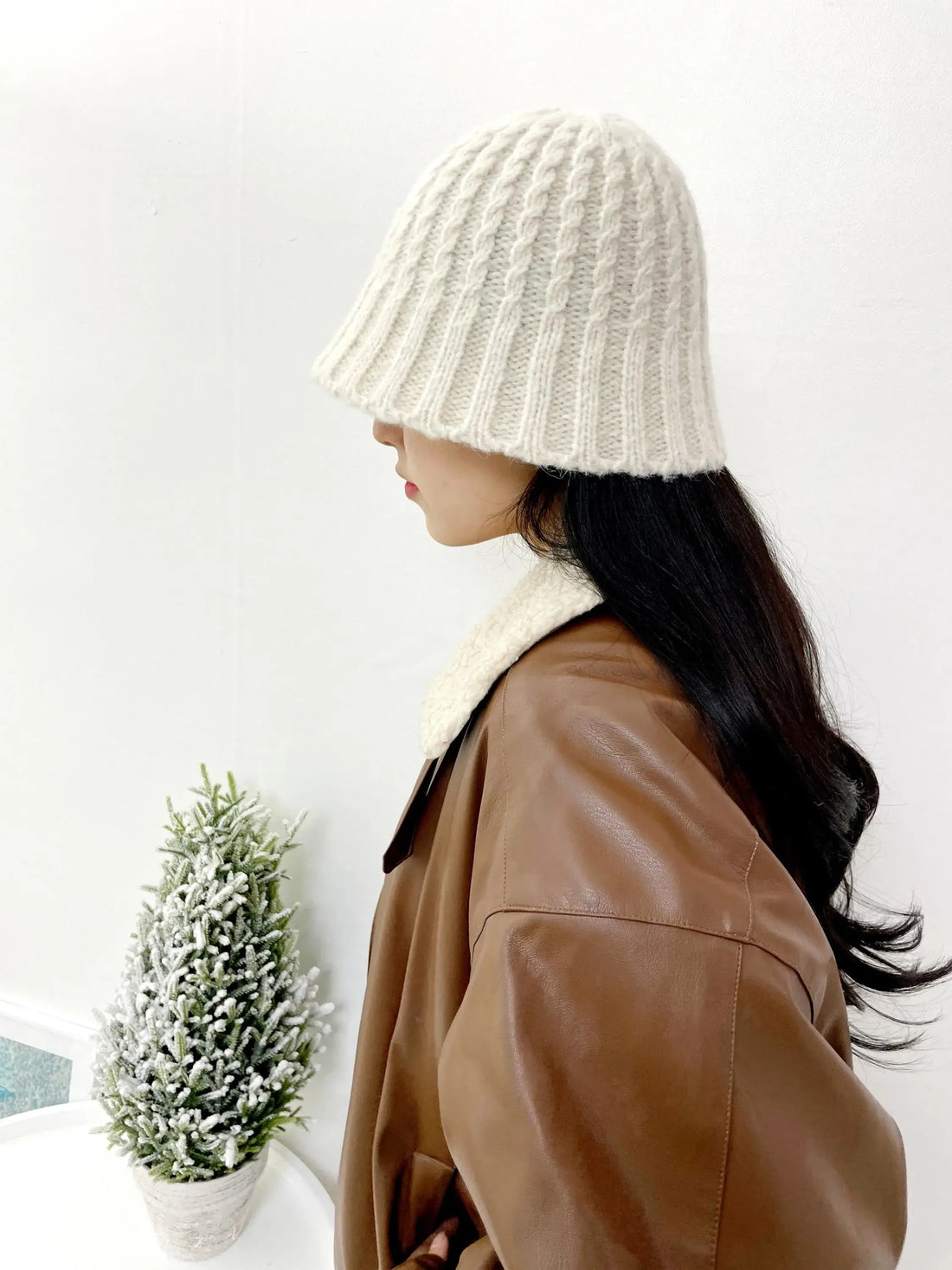 Woman wearing beanie the wool-vol3, a cream knit hat, paired with a brown leather jacket and shearling collar