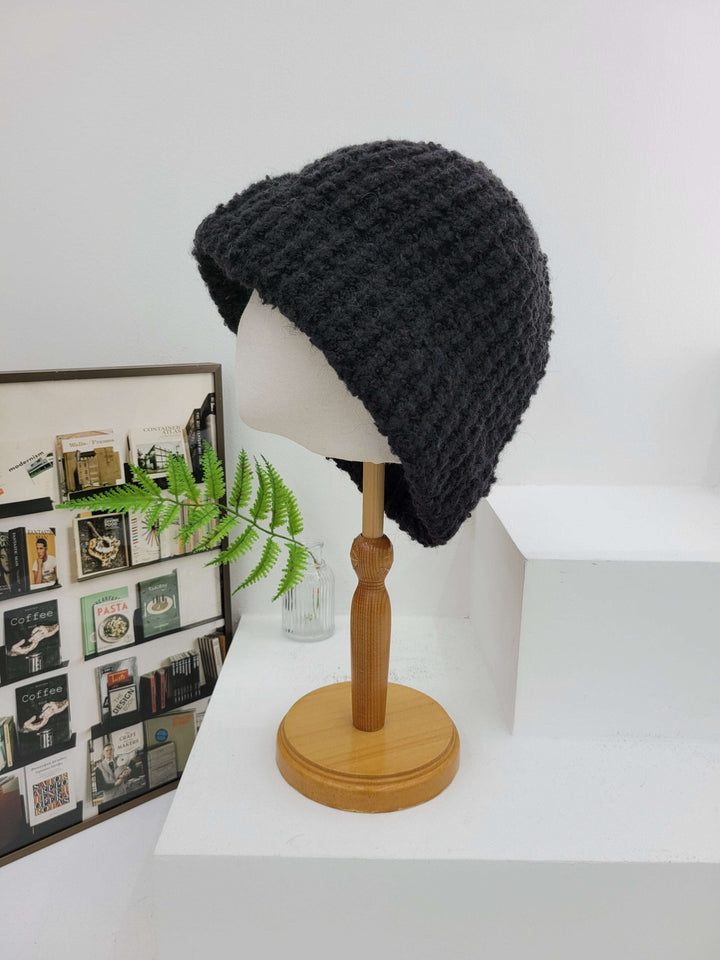 Black knit beanie on a wooden mannequin head against a white background