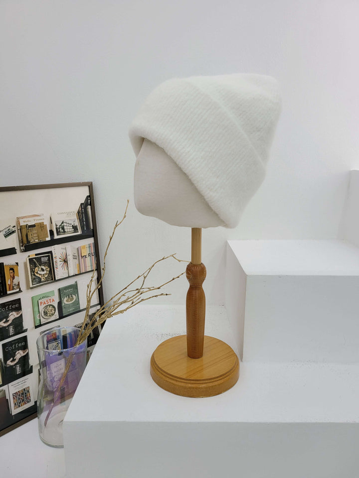 Wall-mounted lamp with a wooden base and white shade on a white wall.
