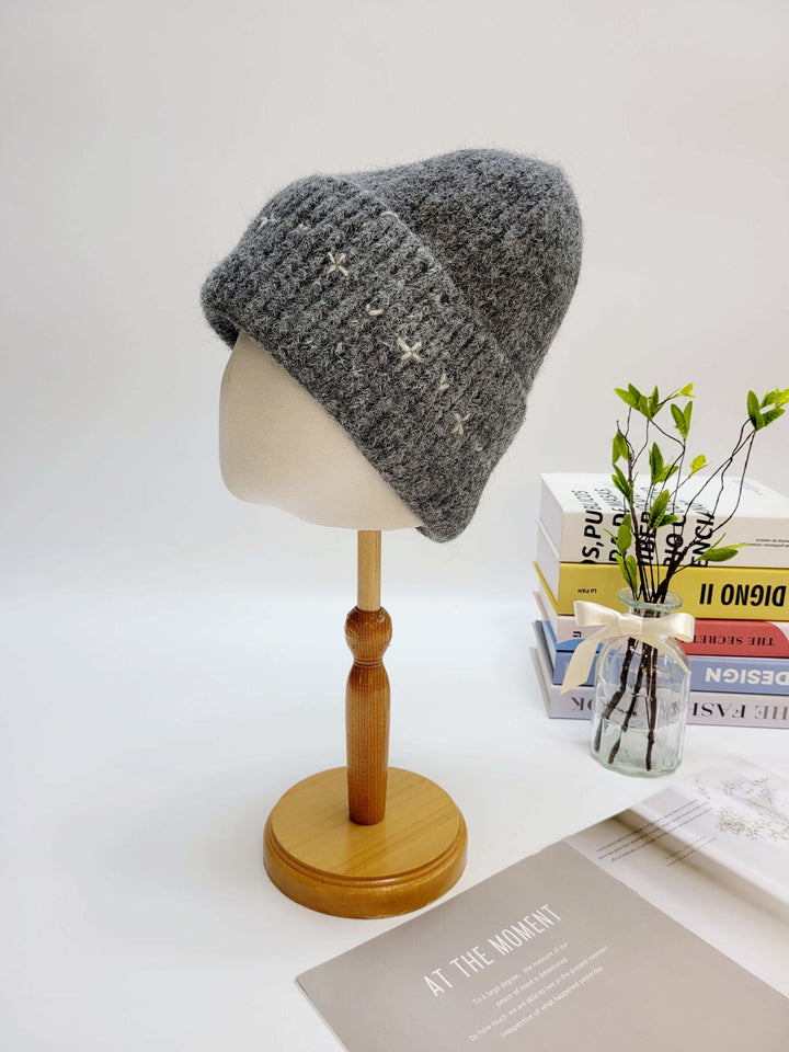 Gray knitted beanie on a wooden mannequin head with a white background