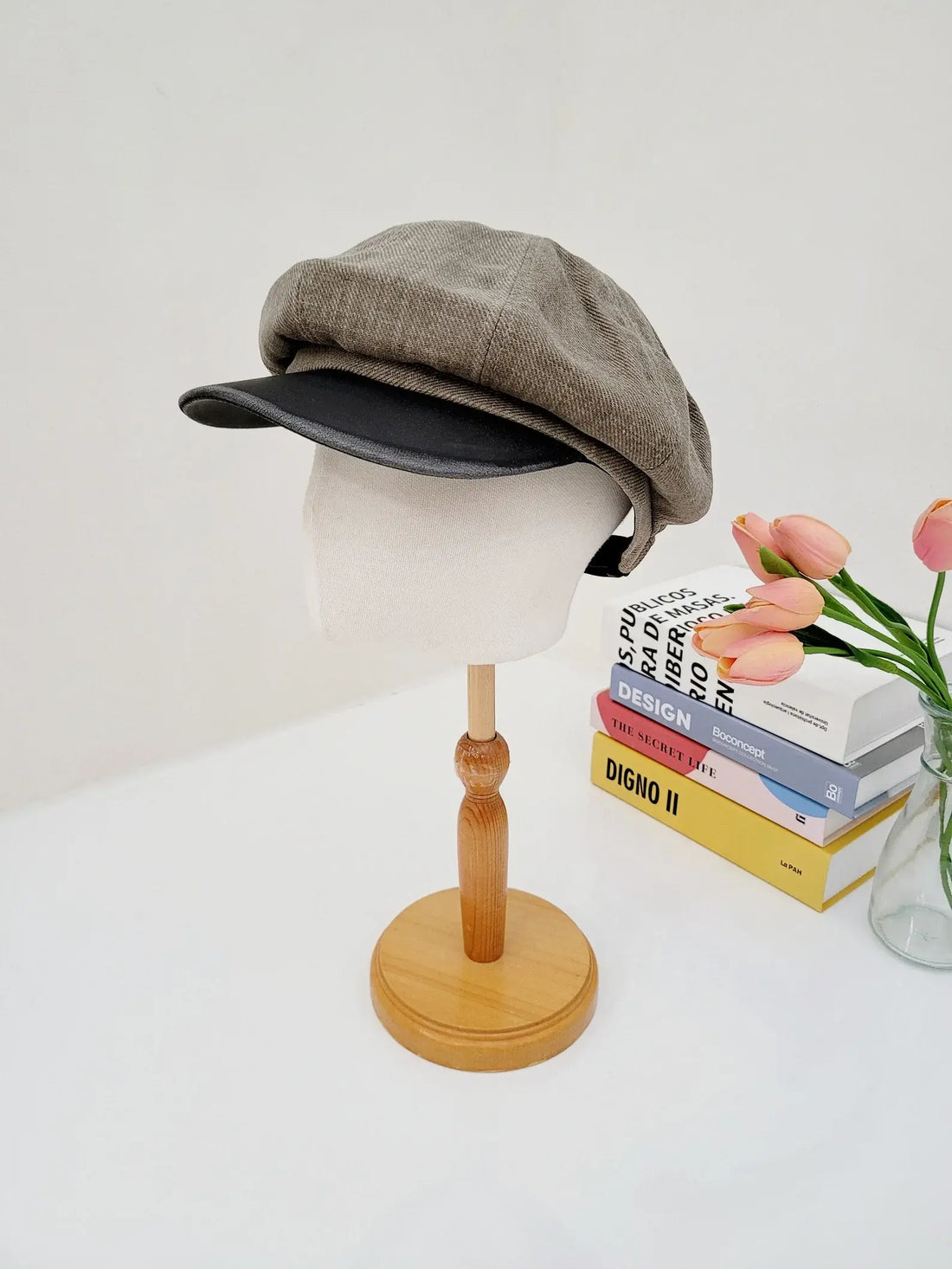 Brown tweed lana beret with a black brim, displayed on a mannequin head, blending classic style with modern flair.