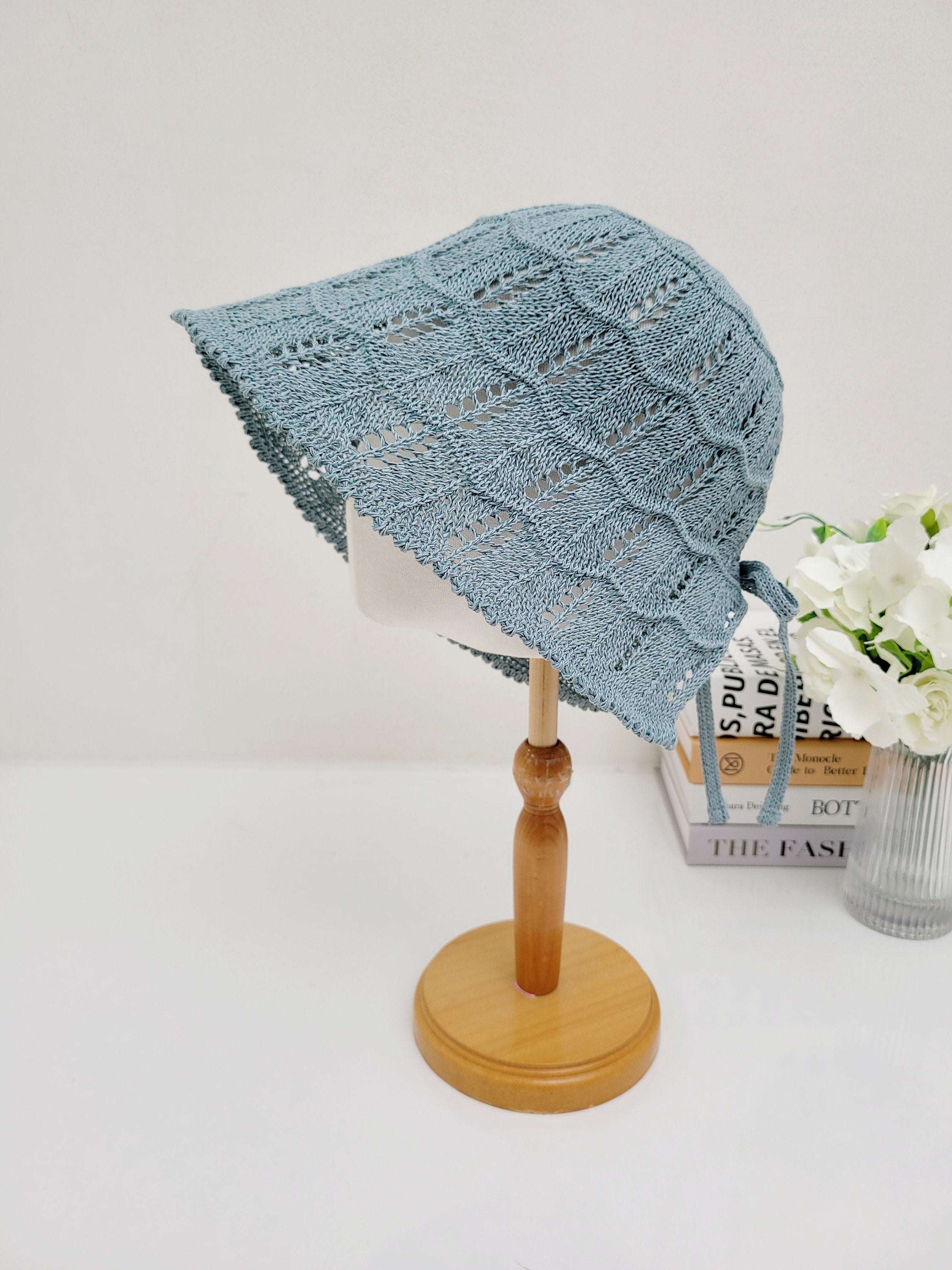 Blue knitted sun hat, ashley's summer favorite, with a delicate openwork pattern and tie detail, displayed on a mannequin head.