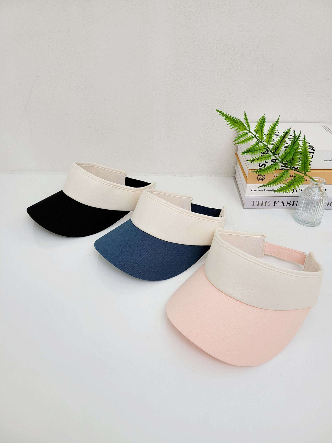 sports sun visor in black, navy, and pink with cream band. Stylish sun protection for outdoor activities.