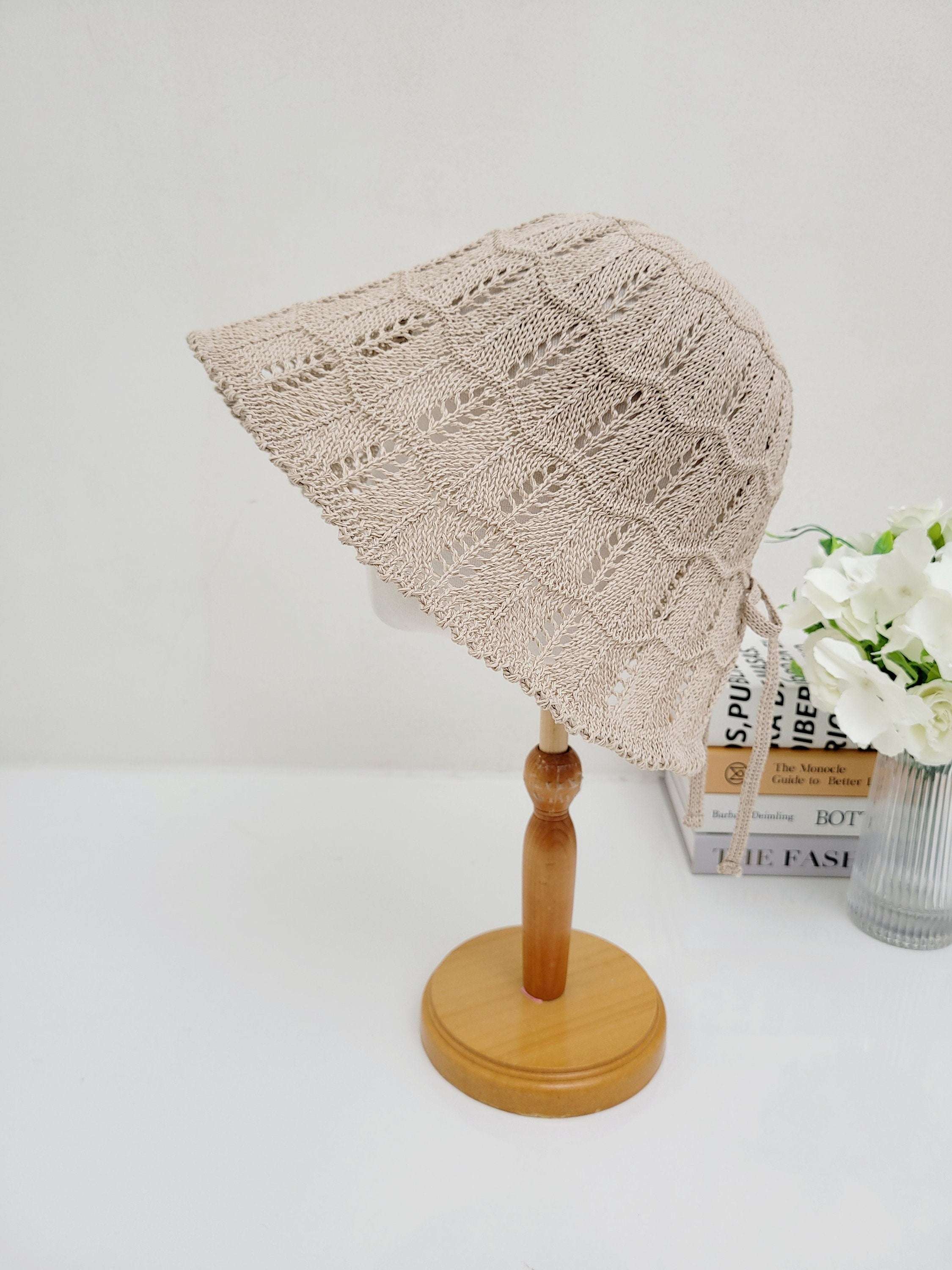ashley's summer favorite: Beige crochet sun hat with a wide brim and tie strings, displayed on a light wood stand.