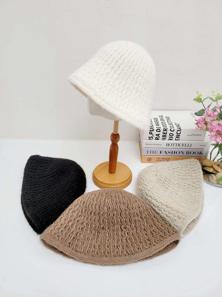 wool bucket hat assortment: black, brown, beige, and white. The white hat is displayed on a wooden stand.