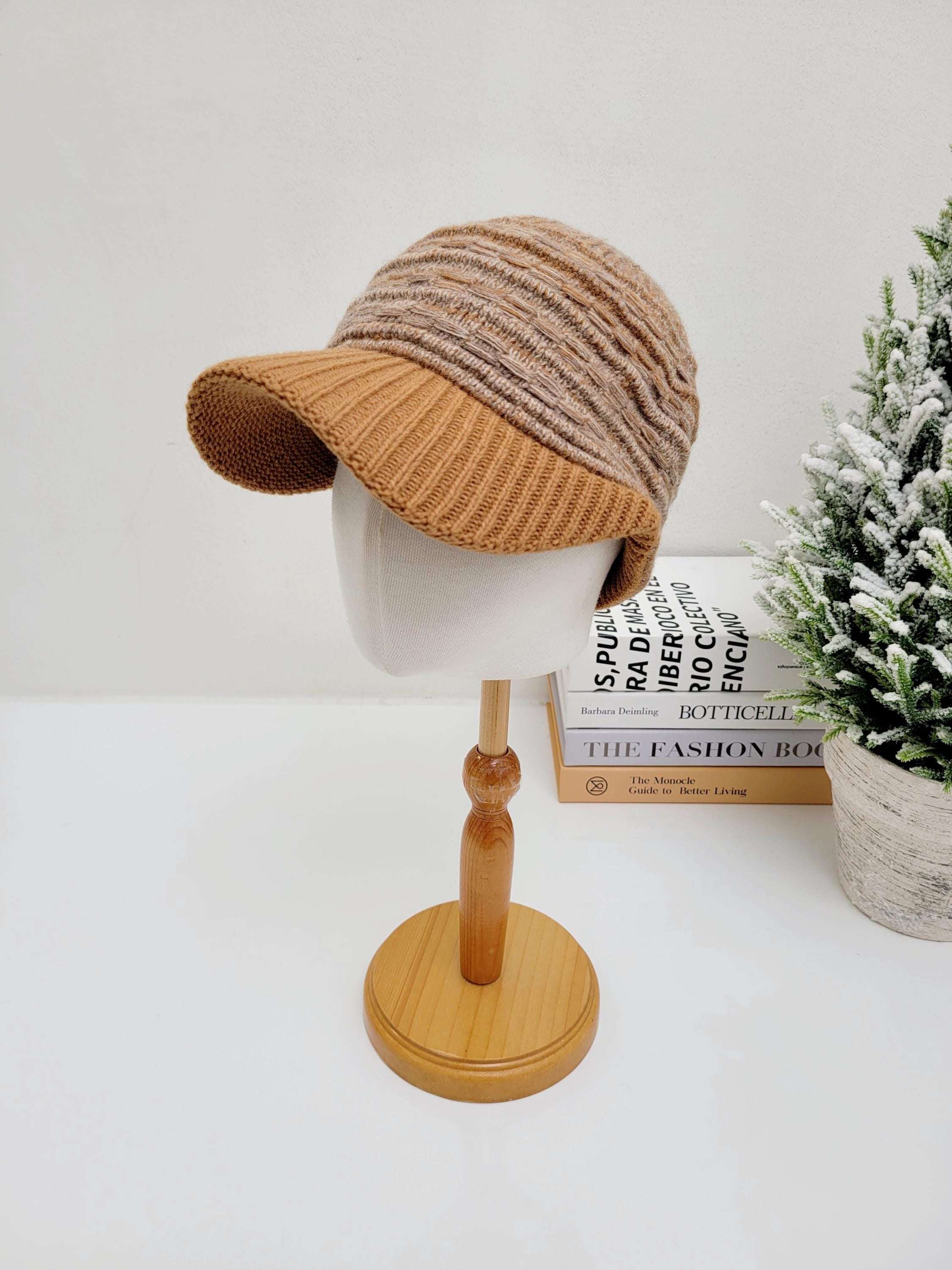 Knitted clara winter cap in brown and beige stripes, displayed on a mannequin head. The cap features a visor and a textured knit pattern.