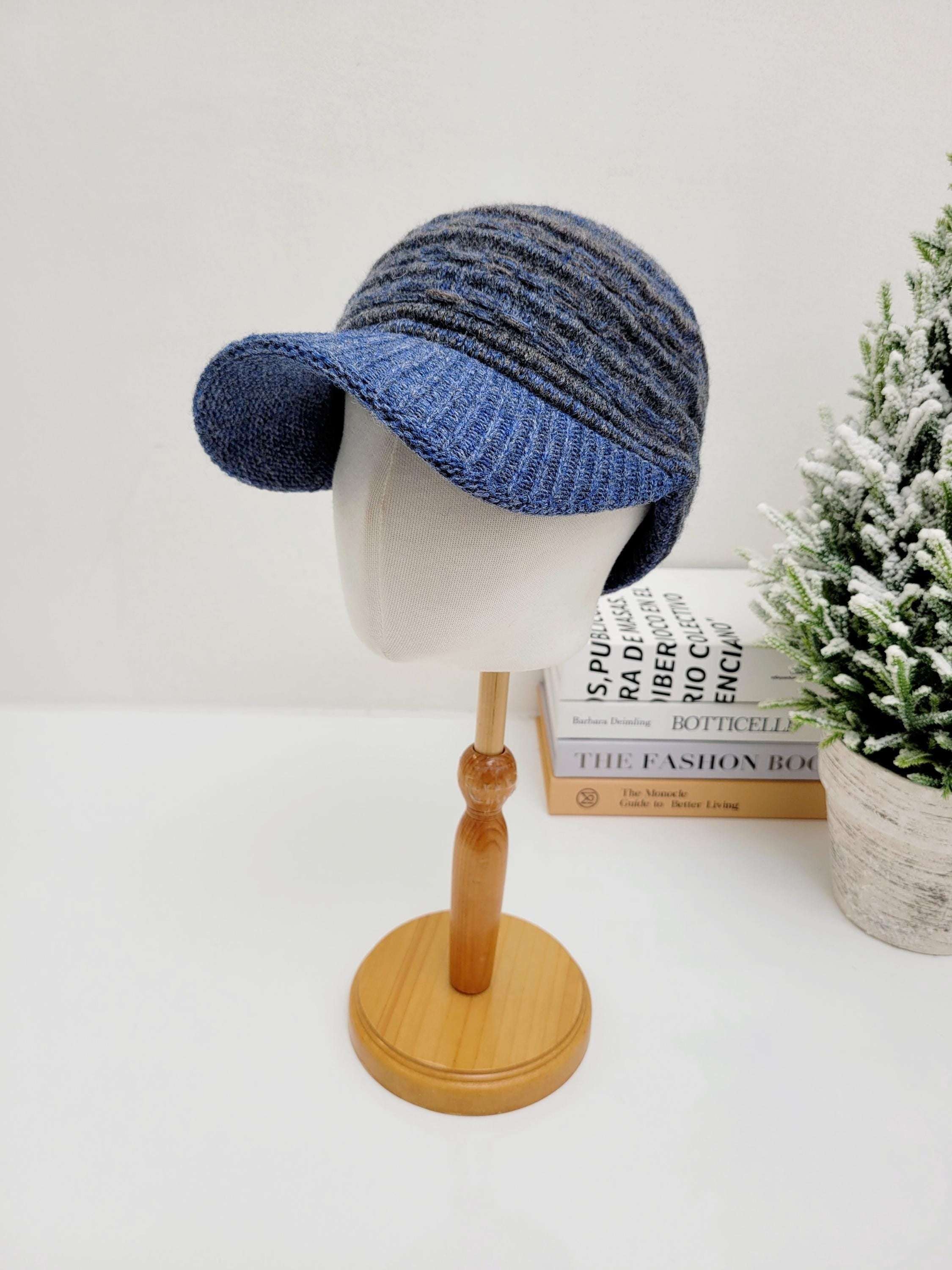 Blue and gray knitted clara winter cap with brim, displayed on a mannequin head. Perfect for cold weather.