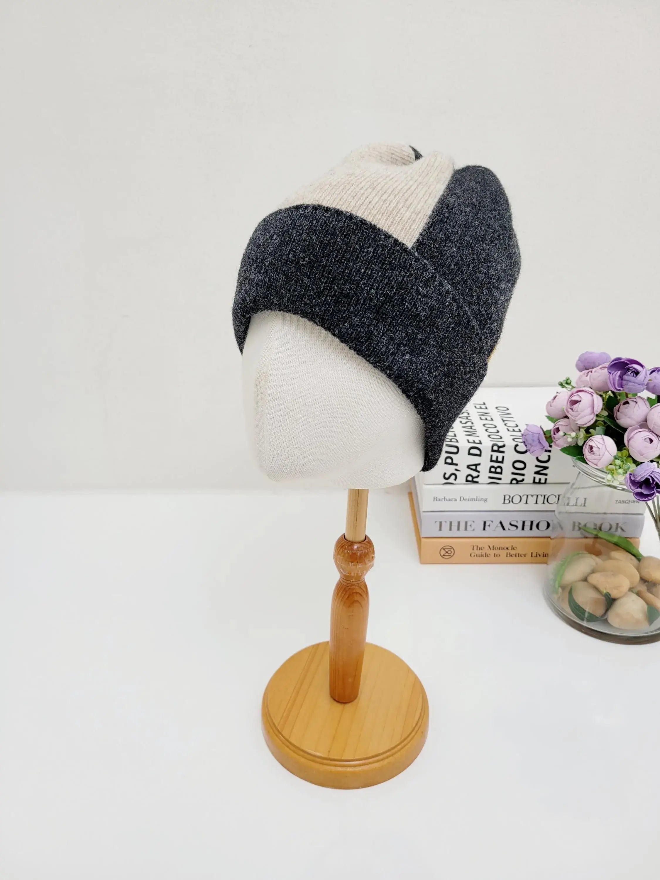 Color block wool beanie in charcoal and cream, displayed on a wooden stand. A stylish and warm winter accessory.