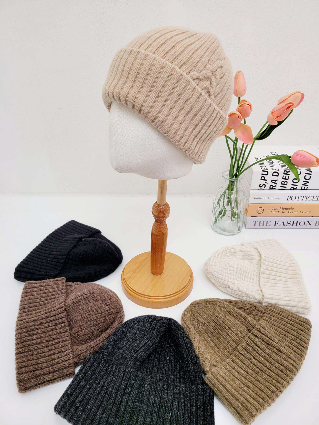 Beige ribbed beanie the wool-vol2 on a mannequin, with other beanies in black, brown, gray, and cream colors displayed around it.