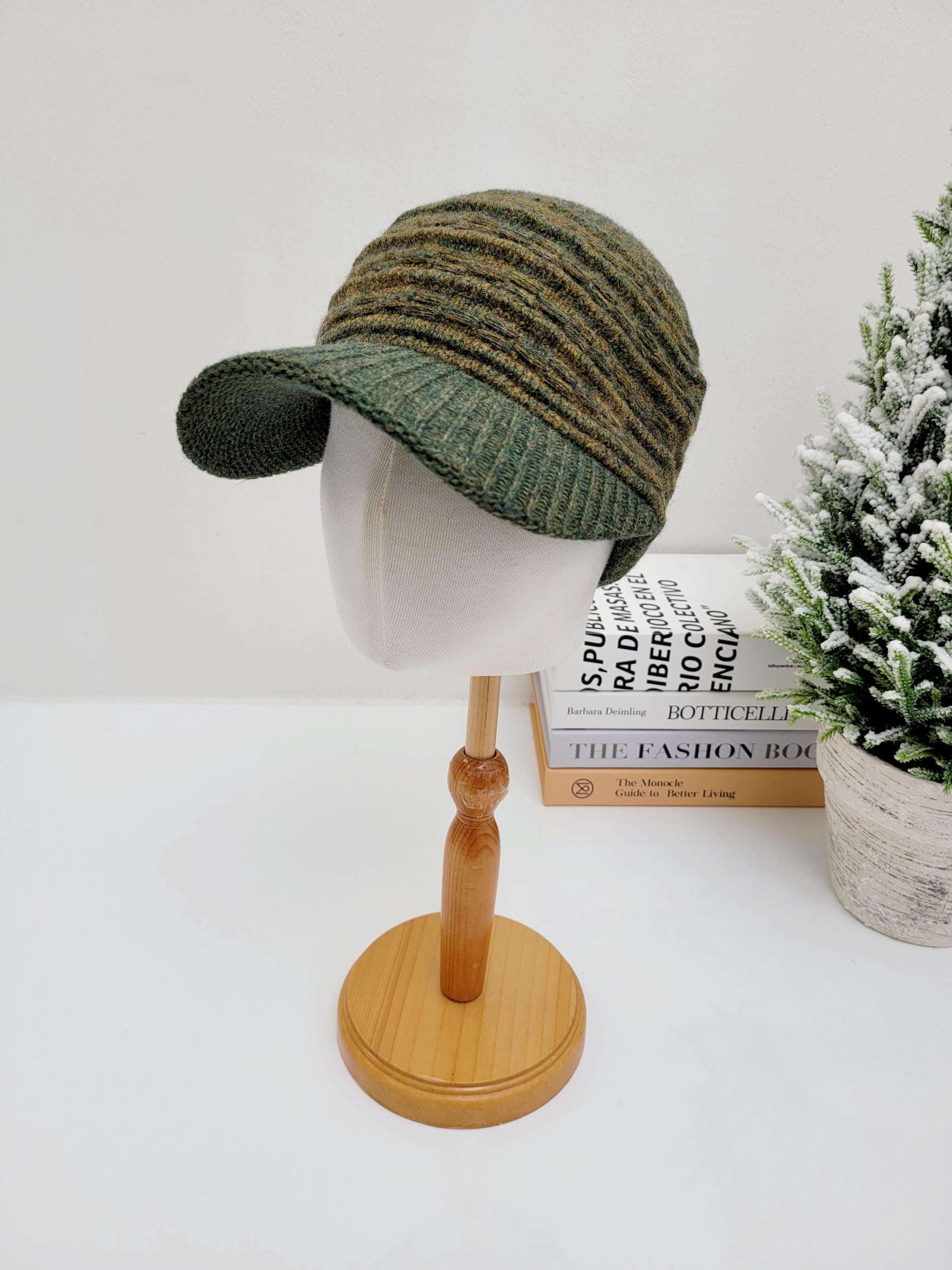 Green and brown knitted clara winter cap with a brim, displayed on a mannequin head.