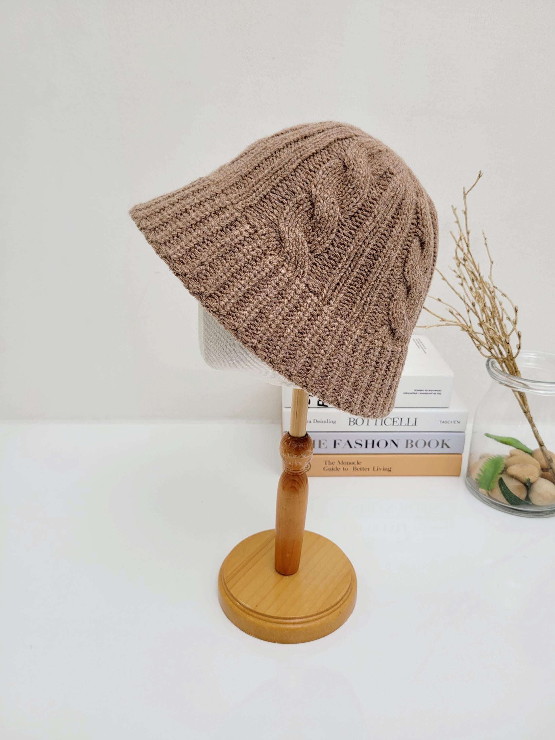 Brown cable knit hat on a wooden stand. A cozy and stylish accessory for cooler weather.