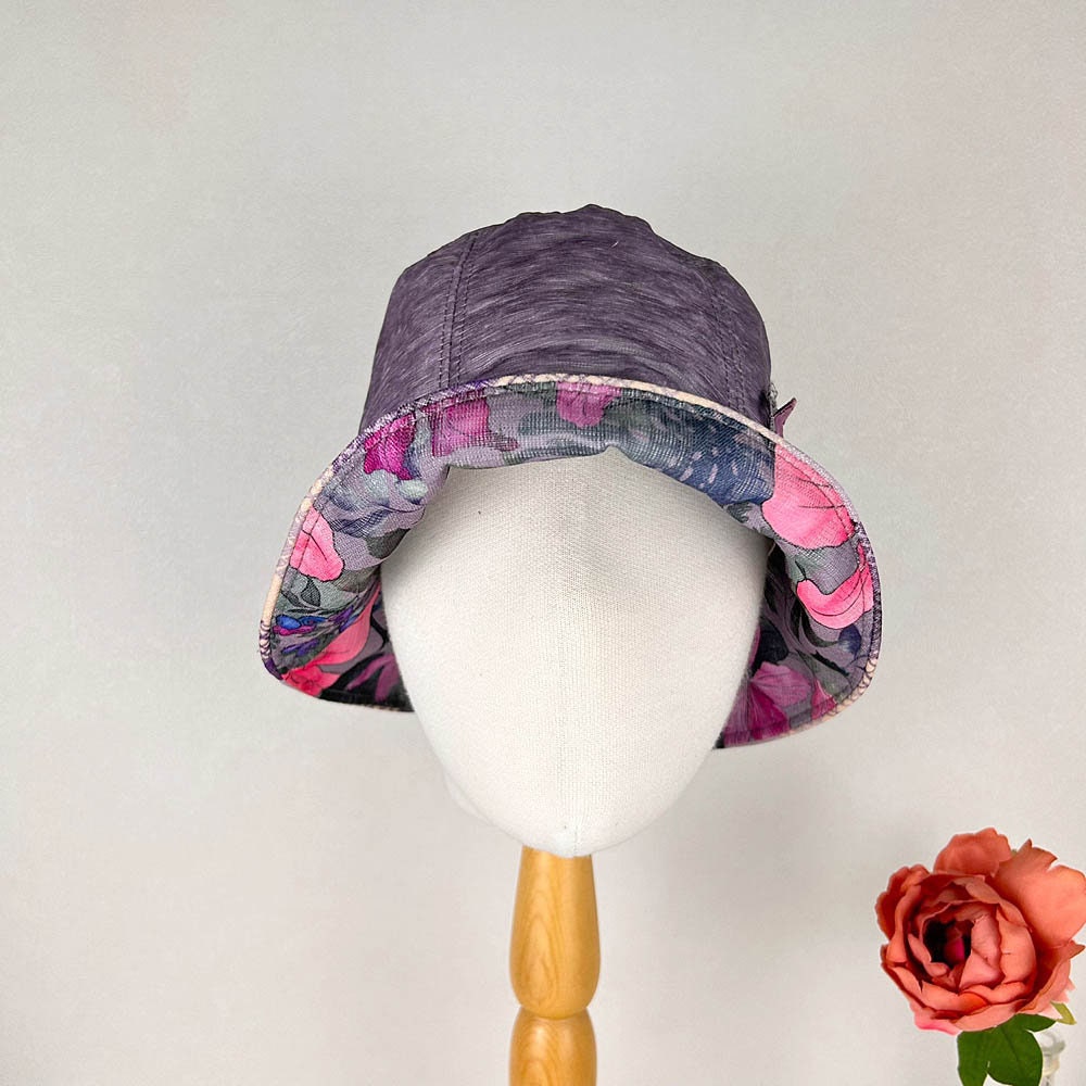 Purple linen bucket-side flower hat with a colorful floral lining, displayed on a mannequin head