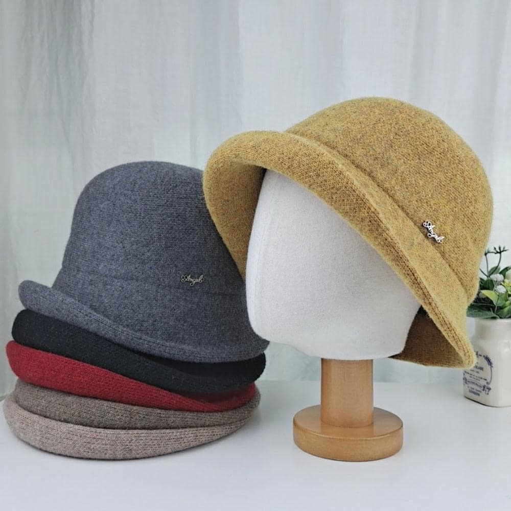 Stack of colorful wool bucket hat, including gray, black, red, and beige. Mustard yellow hat displayed on a stand.