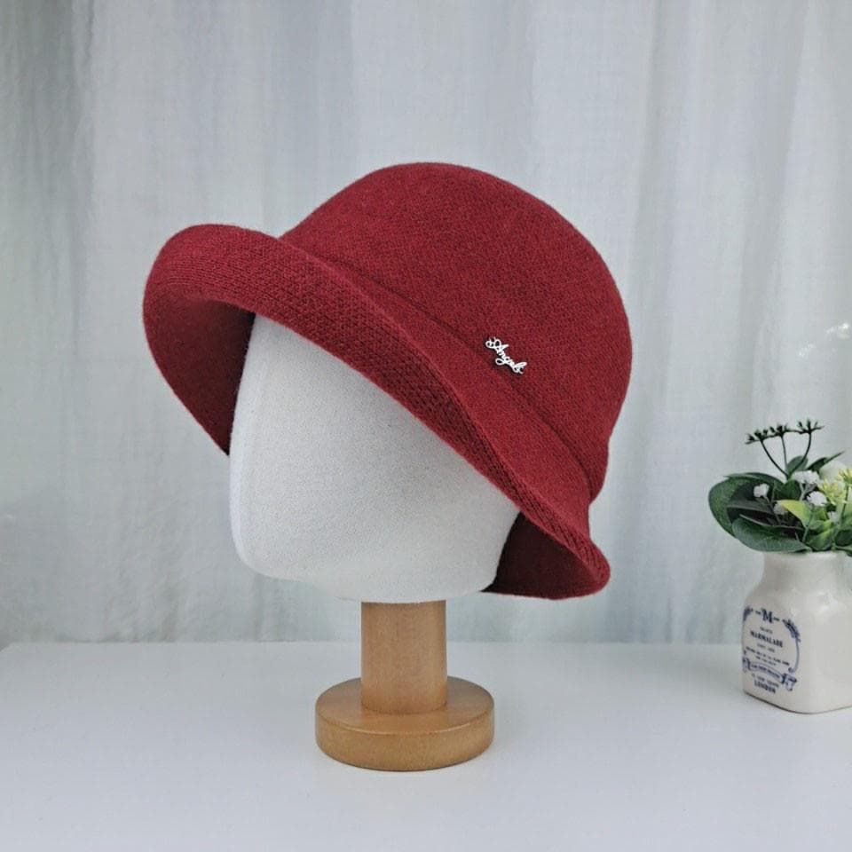 Red colorful wool bucket hat on mannequin head with small metal accent. A stylish winter accessory.