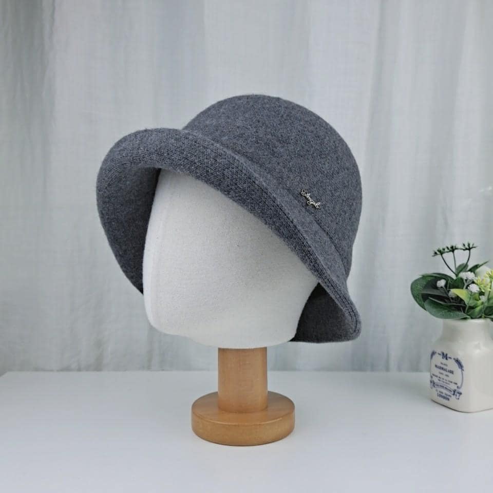Gray knitted cloche hat with a small embellishment, displayed on a mannequin head. The brim is slightly downturned.