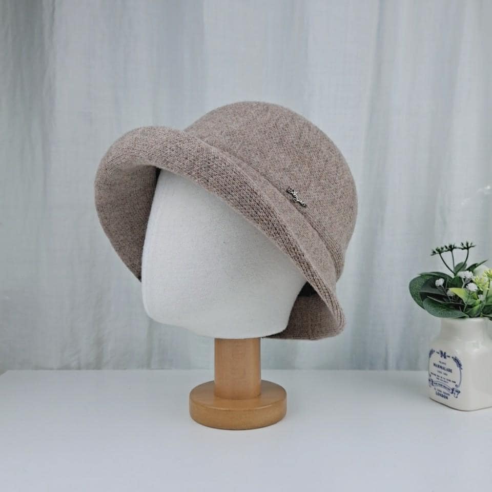 Beige knitted cloche hat with a subtle embellishment, displayed on a mannequin head. Soft, warm, and stylish.