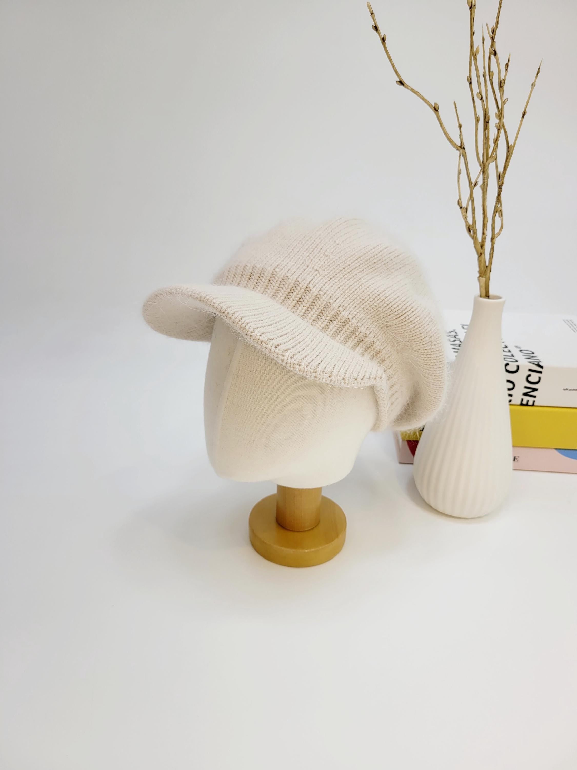 Cream knitted beret, angelina in love, on a mannequin head. Soft, textured knit with a short brim.