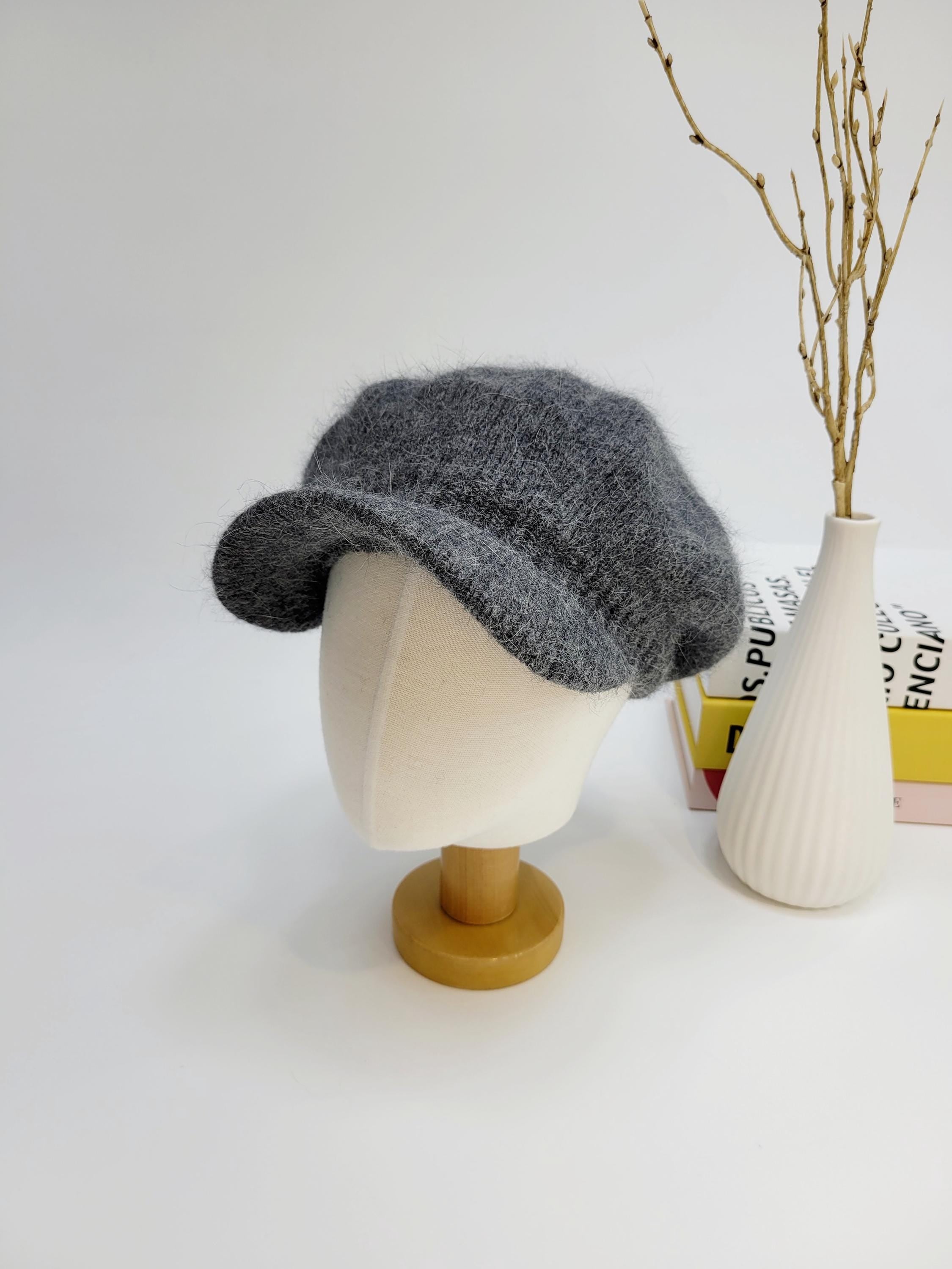 Grey fuzzy beret, angelina in love, displayed on a mannequin head. Soft, stylish headwear with a classic silhouette.