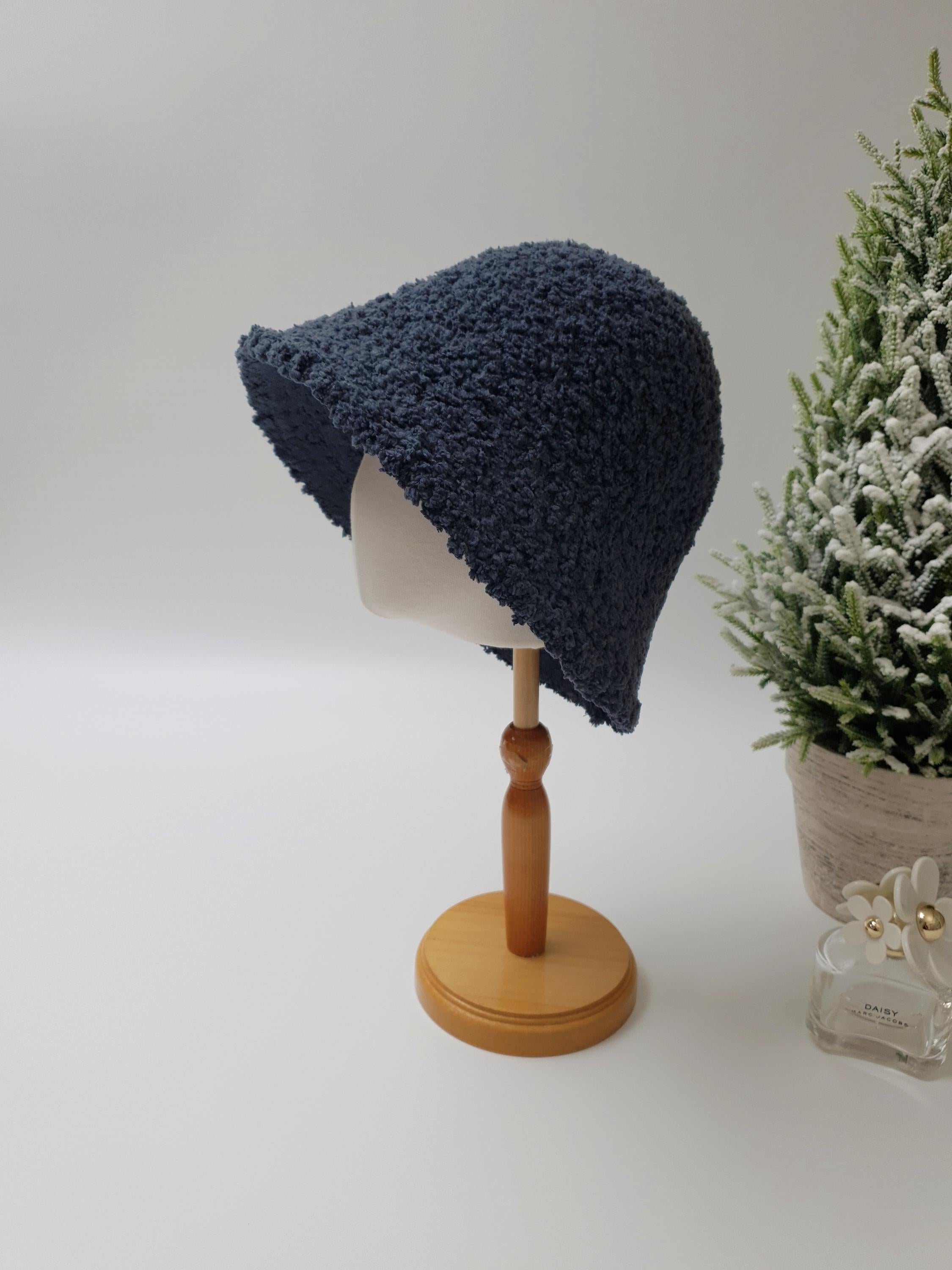 Navy blue sherpa bucket hat on a mannequin head. Soft, textured fabric with a gently sloping brim.