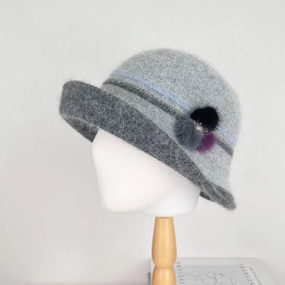 Grey angora elizabeth hat with a dark grey brim, striped band, and pom pom detail, stylish and warm.