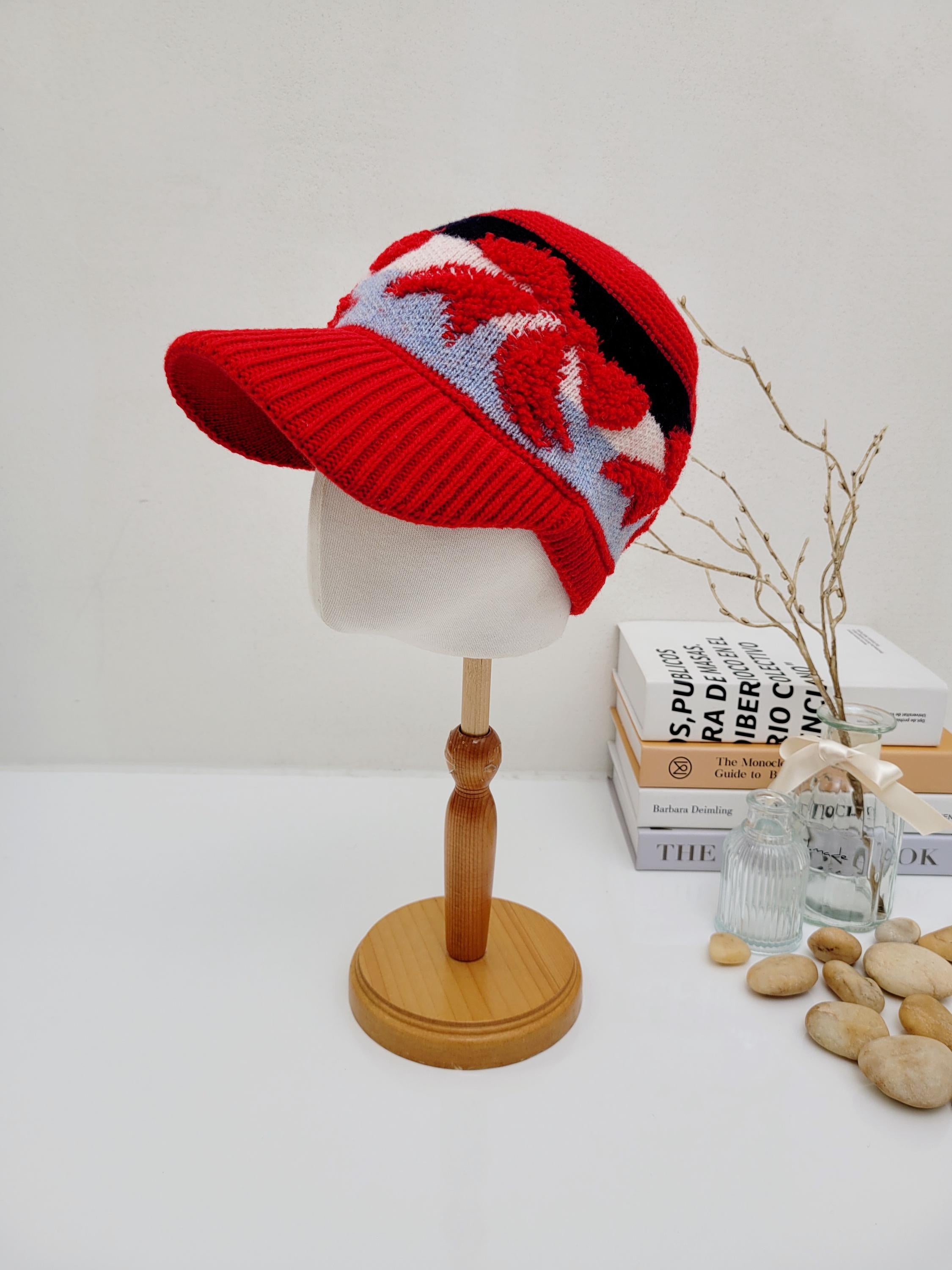 Red earmuff knitted wool cap with a brim and a striking white and blue abstract pattern. A stylish and cozy headwear option.